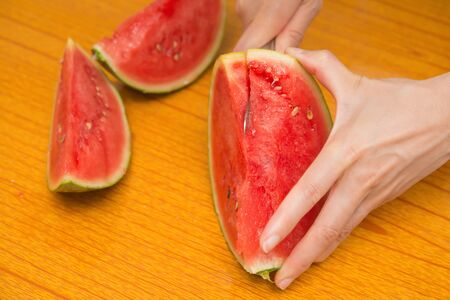 cutting a watermelon with knife on a tableの写真素材