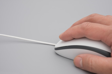 man using a white mouse on a grey background close upの写真素材