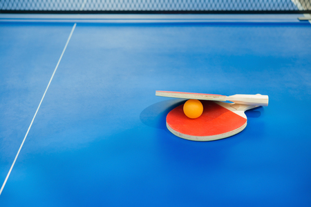 table tennis rackets and ball and net on a blue tableの写真素材