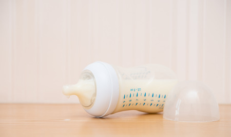 baby bottle and milk on a wood table close up