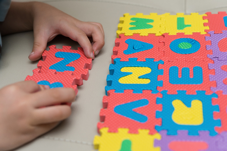 kid playing alphabet jigsaw puzzles on sofaの写真素材
