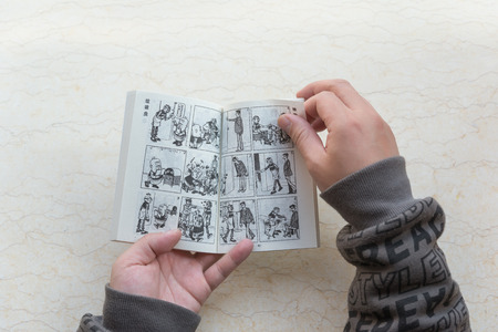 ZhongShan China-January 4:man reading a comic book named Old Master Q on January 4 2017.Old Master Q is a popular Hong Kong comic created by Alfonso Wong and appeared in 1962 and serialised in 1964.のeditorial素材