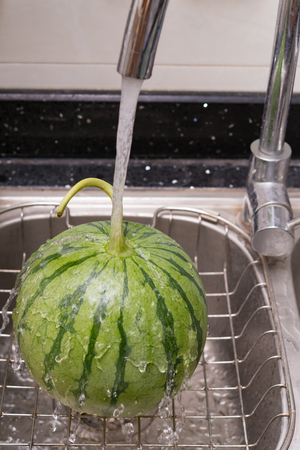 cooling a watermelon on sink with waterの写真素材