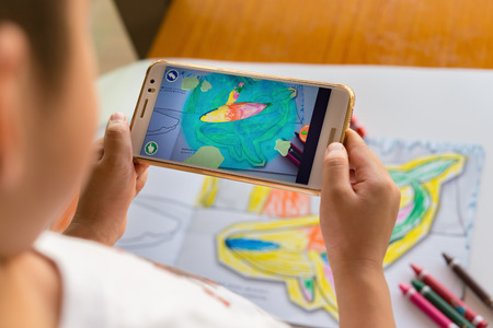 Zhongshan,China-August 8, 2017:kid playing Augmented Reality popup paintings of a filled dolphin via mobile. AR and VR games become more and more popular.のeditorial素材