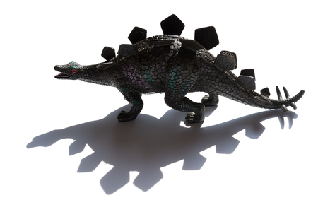 black stegosaurus toy with shadow on a white backgroundの写真素材