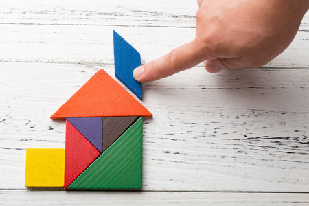 finishing the last bit of wooden tangram in a house shapeの写真素材
