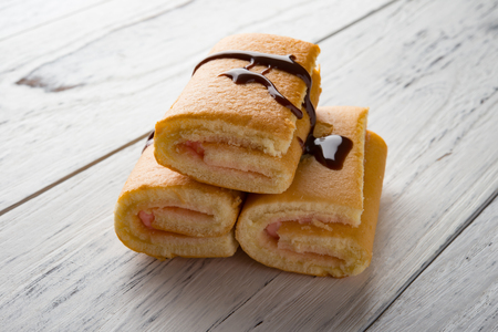 strawberry flavor sweet rolls with liquefied chocolate on white woodの写真素材