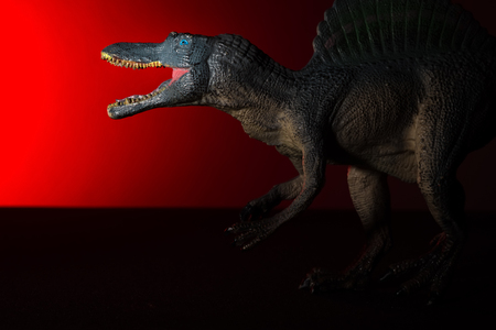 spinosaurus with spot light on the head and red light on backgroundの写真素材