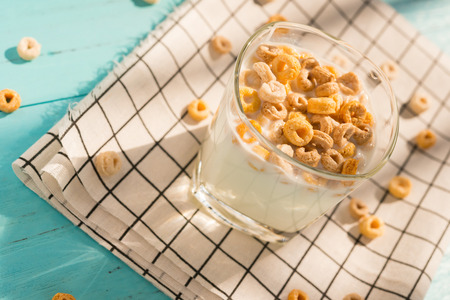 top view cup of milk with cereal rings in a sunny morning as healthy breakfastの写真素材