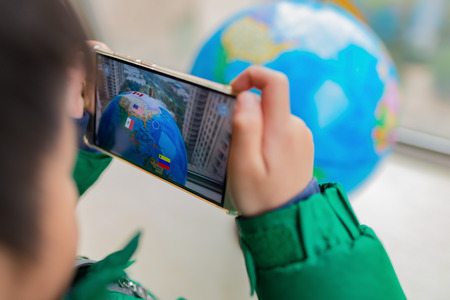 Zhongshan,China-February 7, 2018:kid playing Augmented Reality popup globe with flags via mobile. AR and VR games become more and more popular.のeditorial素材