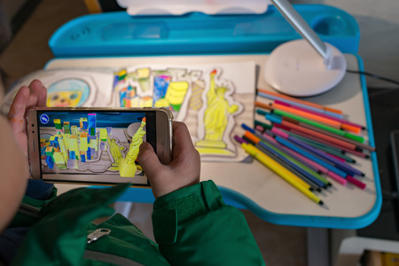 Zhongshan,China-February 8, 2018:kid playing Augmented Reality popup paintings of a color filled Statue Of Liberty and high buildings via mobile. AR and VR games become more and more popular.のeditorial素材