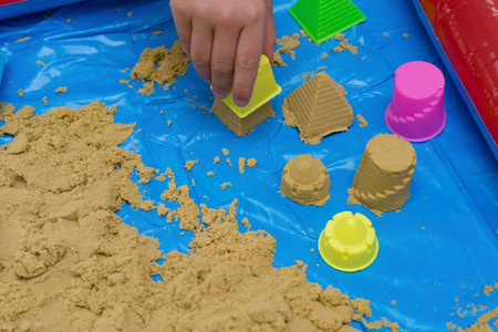 kid making different shapes by sand with moulds