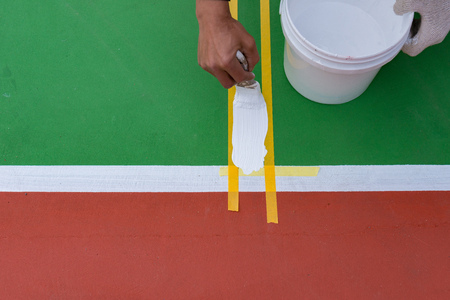 worker painting the sideline on the floor for an outdoor stadiumの写真素材