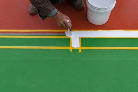 worker painting the sideline on the floor for an outdoor stadiumの写真素材