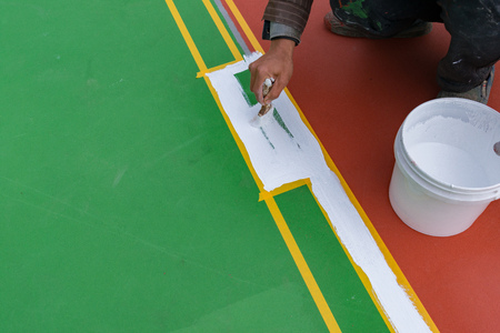 worker painting the sideline on the floor for an outdoor stadiumの写真素材