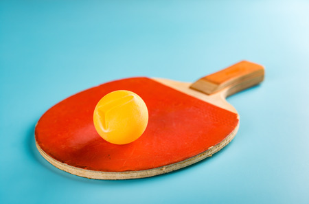 old table tennis racket and a dented ball on a blue backgroundの写真素材