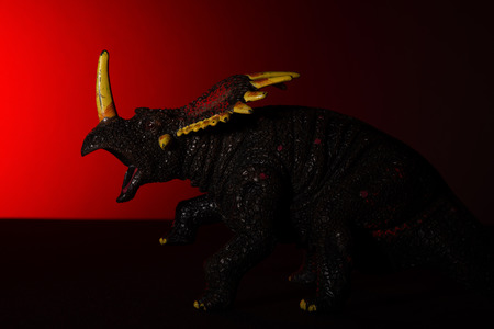triceratops with spot light on the head and red light on backgroundの写真素材