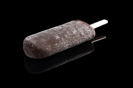 chocolate coated ice stick on black background with reflectionの写真素材