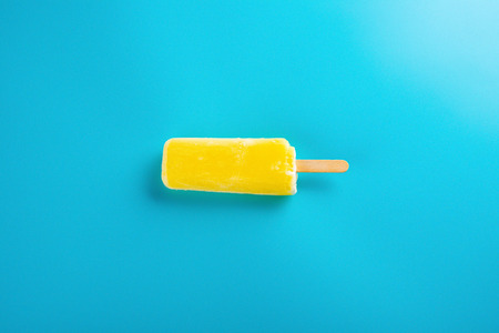 yellow  ice lolly on a blue backgroundの写真素材