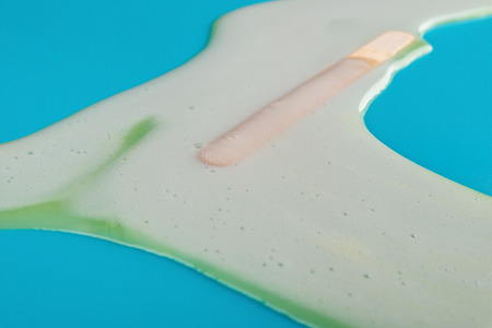 side view ice cream melting completely on blue backgroundの写真素材