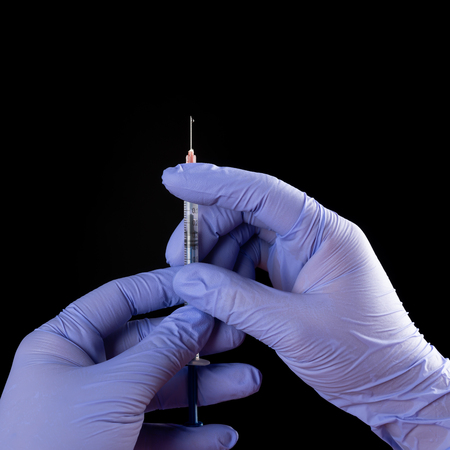 hands holding syringe medical injection on black backgroundの写真素材