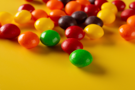 studio shot colorful chocolate buttons on yellow background