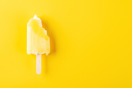 yellow ice cream stick with bites on a yellow backgroundの写真素材