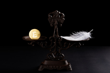 bitcoin and feather on a balanced scale concept of the value of bitcoins worthlessの写真素材