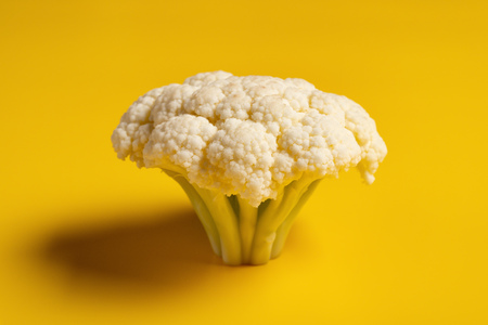 piece of fresh cauliflower on a yellow backgroundの写真素材