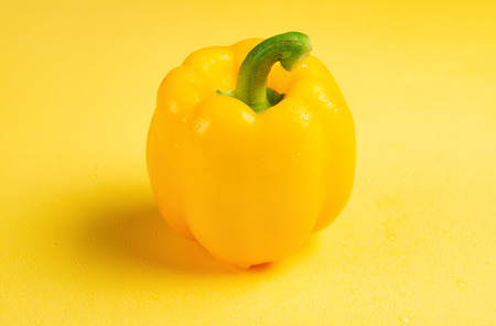 fresh yellow bell pepper with drips on a yellow background