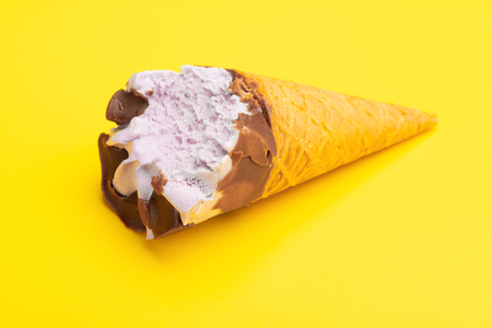 sweet potato flavor ice cream cone with a bite on a yellow backgroundの写真素材