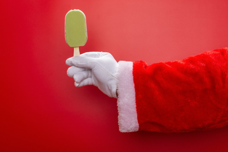 santa claus holding a green bean flavored ice-cream in front of a red background