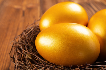 gold eggs on a nest on wooden background close upの写真素材