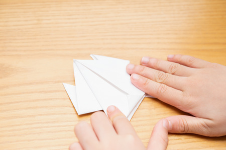kid folding an origami frog by white paperの写真素材