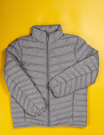 mens insulated down jacket with pockets on a yellow backgroundの写真素材