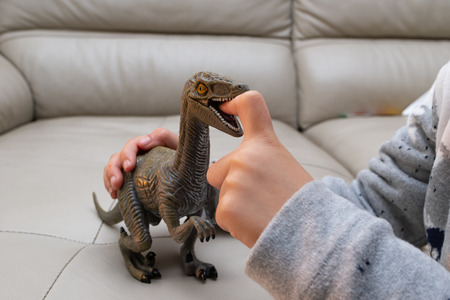 kid playing a Deinonychus toy and putting his finger inside the mouthの写真素材