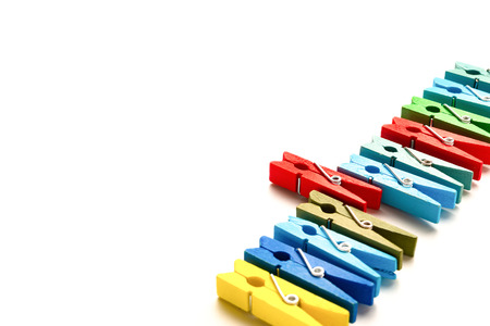 colorful wooden clothespins with one sticks out on a white backgroundの写真素材