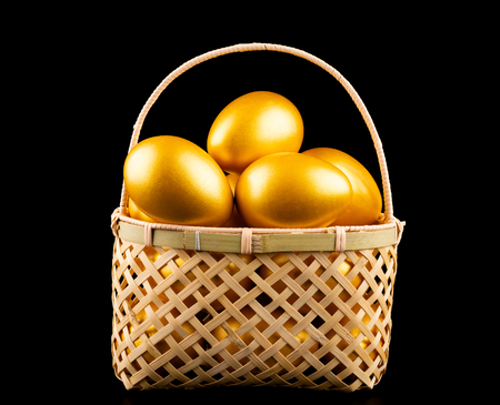 gold eggs in a basket on black backgroundの写真素材