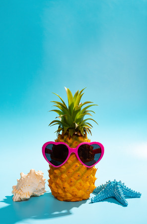 pineapple wears a heart shape sun glasses with starfish and sea shell nearby concept of summer vacationの写真素材