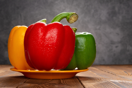 fresh colorful bell peppers with drips on wood tableの写真素材