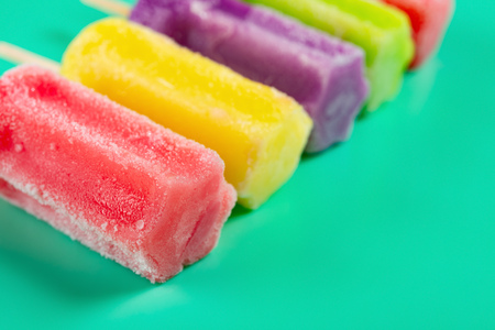 multi-color ice cream stick line up on green background with copy space