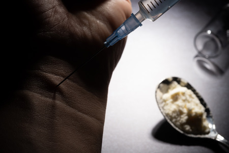 drugster injecting his arm in dark roomの写真素材