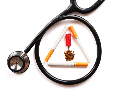 Cigarette with firecracker and tobacco shaped like a warning sign surrounded by stethoscope. Quit smoking concept.の写真素材