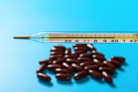 mercury thermometer at  40 degrees centigrade with dozens capsules at backgroundの写真素材