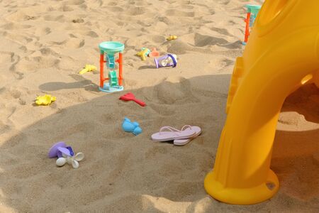 toy house and plastic digger etc on sand in a sunny day