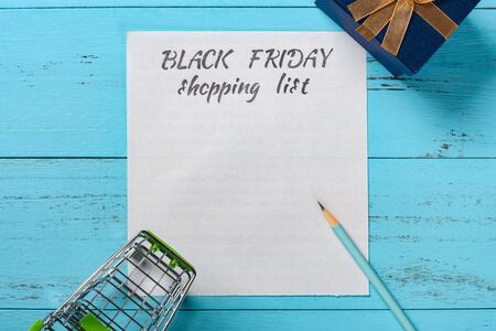 top view hand written black friday shopping list with a pencil and shopping cart and present boxの写真素材