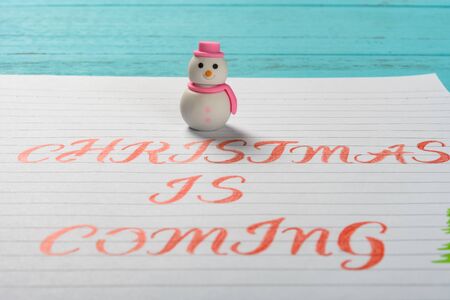 paper written with Christmas is coming and a snowman on top