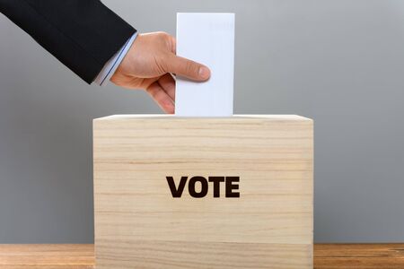 man inserting his ticket to a vote box the word of VOT