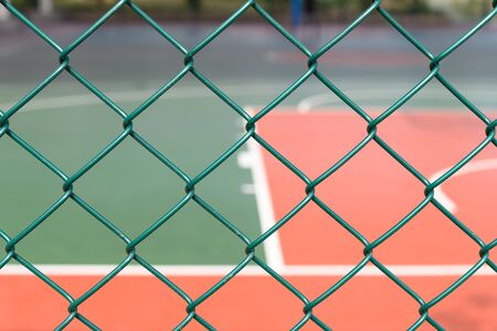 outdoor basketball court behind a metal fence horizontal compositionの写真素材
