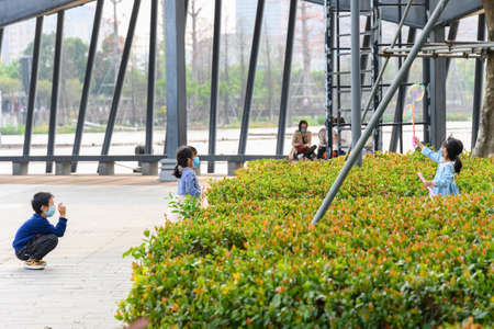 ZhongShan China-March 14,2020:Children playing in a park. Everyone wears mask to avoid the COVID-19.のeditorial素材